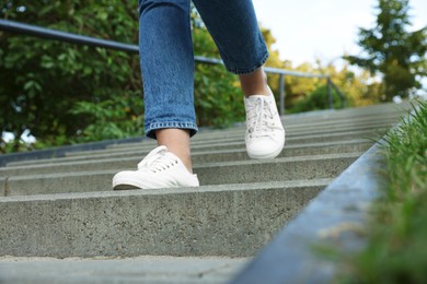 Photo of Woman in stylish black sneakers walking down stairs, closeup