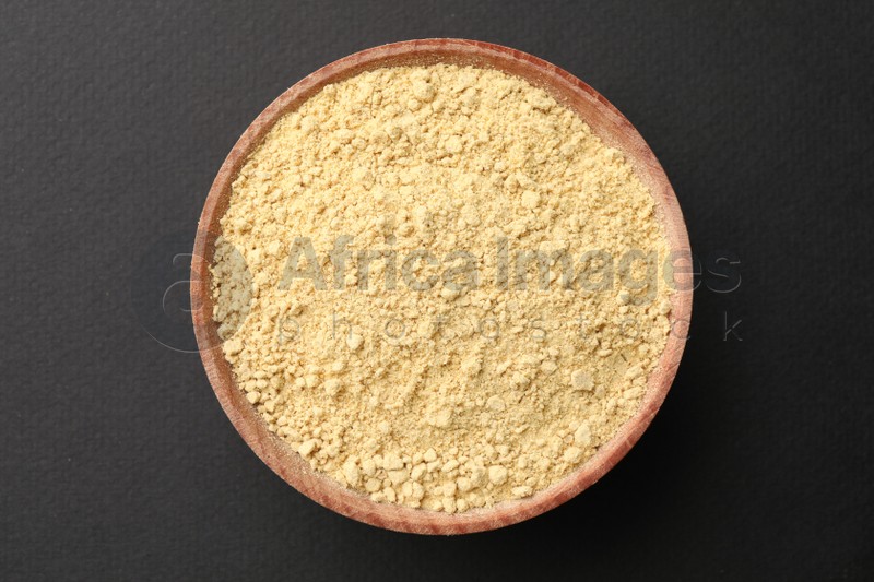 Photo of Wooden bowl with mustard powder on grey background, top view