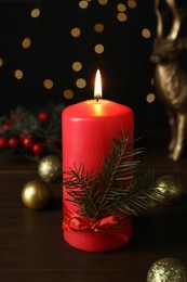 Red burning candle and Christmas decor on wooden table