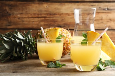 Photo of Delicious fresh pineapple juice with mint on wooden table