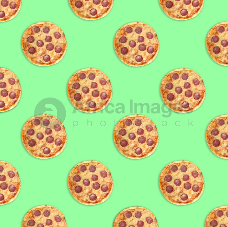 Many delicious pepperoni pizzas on green background, flat lay. Seamless pattern design