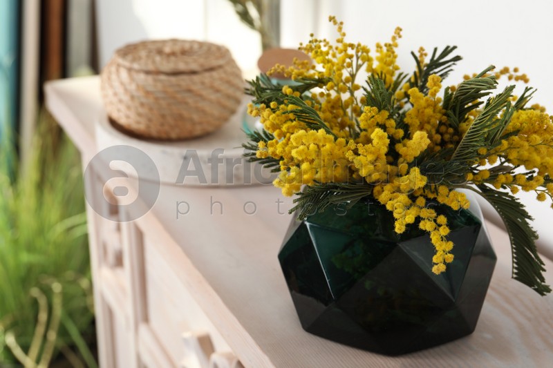 Beautiful mimosa flowers on chest of drawers indoors, space for text
