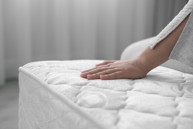 Photo of Woman touching soft white mattress indoors, closeup