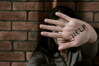 Photo of Domestic violence concept. Woman hiding her face, focus on hand with written word Help