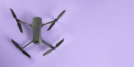 Modern drone with camera on lilac background, top view. Space for text