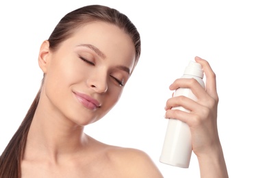 Young woman applying thermal water on face against white background. Cosmetic product