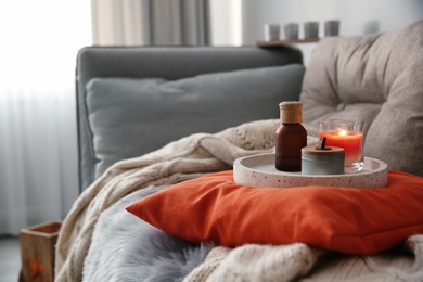 Photo of Aroma candles and oil on sofa in living room. Interior design