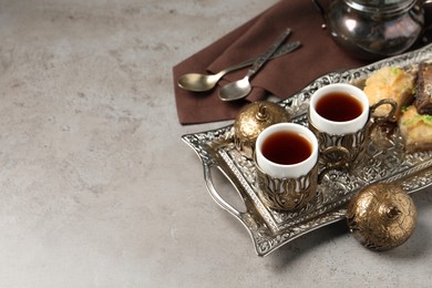 Photo of Tea and baklava served in vintage tea set on grey table, space for text