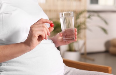 Pregnant woman taking pill at home, closeup