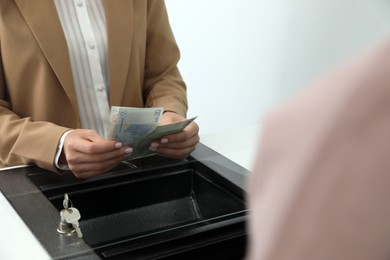 Photo of Cashier with money at currency department window in bank, closeup