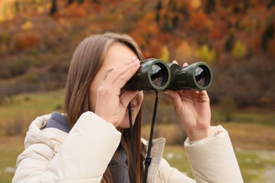 Photo of Woman looking through binoculars in beautiful mountains, closeup