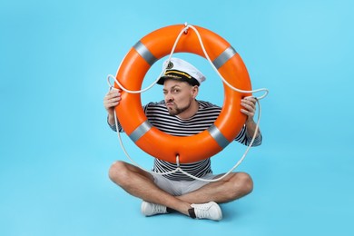 Funny sailor with orange ring buoy on light blue background