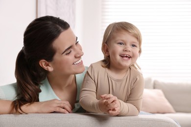 Photo of Mother with her cute little daughter on sofa at home