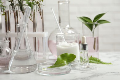 Organic cosmetic products, natural ingredients and laboratory glassware on white marble table