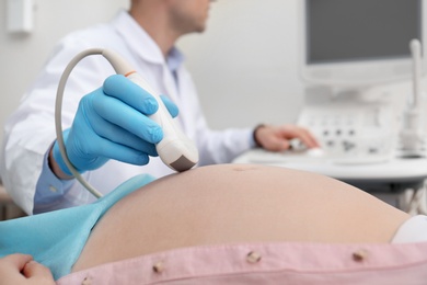 Pregnant woman undergoing ultrasound scan in clinic, closeup