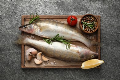 Fresh raw pike perches and ingredients on grey table, top view. River fish