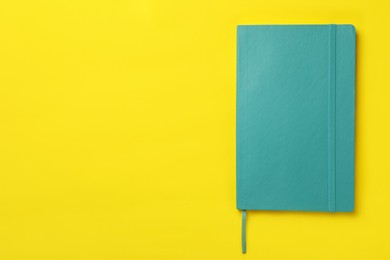 New stylish planner with hard cover on yellow background, top view. Space for text