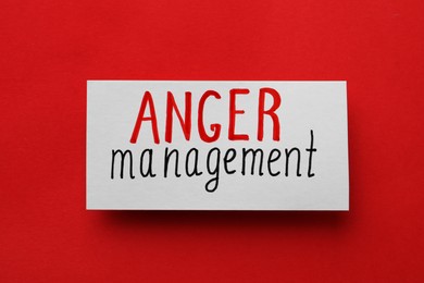 Card with words Anger Management on red background, top view