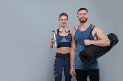 Photo of Athletic people with headphones, thermo bottle and fitness mat on grey background, space for text