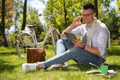 Man working with tablet on grass in park