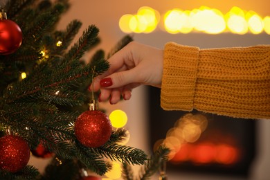 Photo of Woman decorating Christmas tree at home, closeup