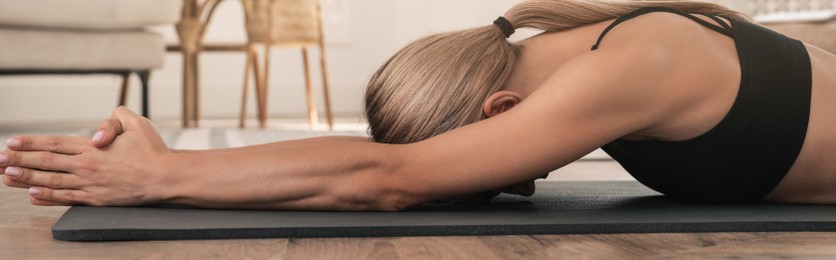 Woman practicing yoga in room at home. Horizontal banner design 