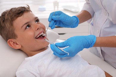 Dentist examining little boy's teeth in modern clinic