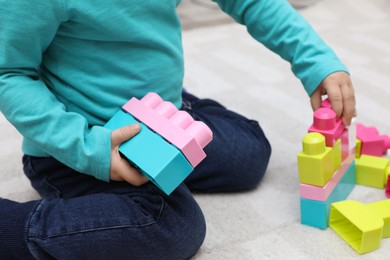 Little child playing with building blocks on carpet, closeup