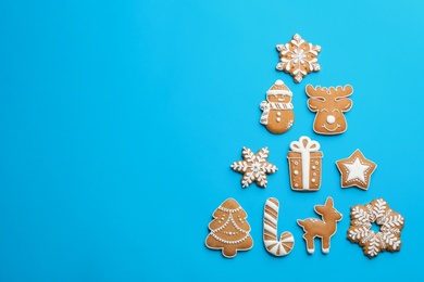 Photo of Delicious gingerbread cookies arranged in shape of Christmas tree on light blue background, flat lay. Space for text
