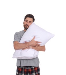 Sleepy handsome man hugging soft pillow on white background
