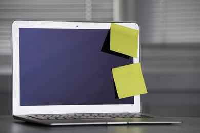 Laptop with blank sticky notes on grey office desk. Space for text