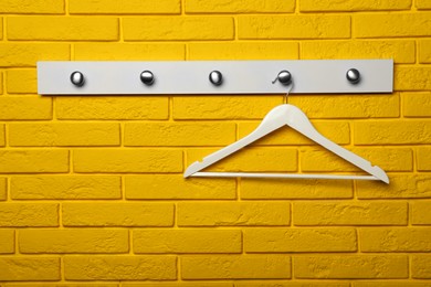 Photo of Rack with empty clothes hanger on yellow brick wall