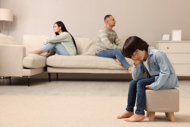 Photo of Sad couple with relationship problems at home, focus on their upset child