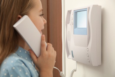 Cute little girl answering intercom call indoors, closeup