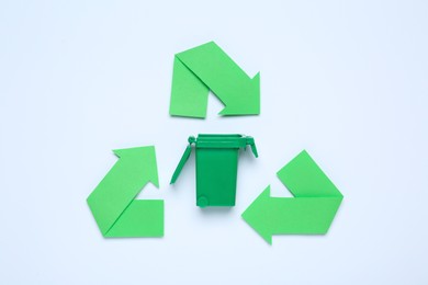 Recycling symbol and trash bin on white background, top view
