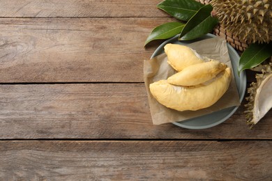 Fresh ripe durians and leaves on wooden table, flat lay. Space for text