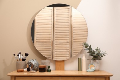 Wooden dressing table with round mirror and makeup products