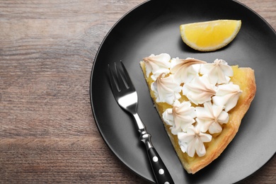 Piece of delicious lemon meringue pie served on wooden table, flat lay. Space for text