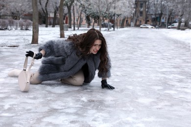 Young woman fallen on slippery icy pavement in park