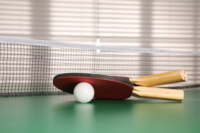 Rackets and ball on ping pong table indoors