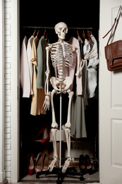 Artificial human skeleton model among clothes in wardrobe room