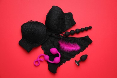 Sex toys and lingerie on red background, flat lay