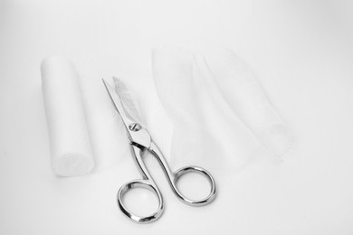Medical cotton bandage and scissors on white background