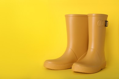 Pair of bright rubber boots on yellow background.  Space for text