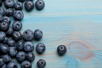 Tasty fresh blueberries on light blue wooden table, flat lay. Space for text