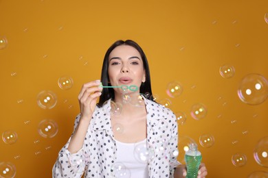 Photo of Young woman blowing soap bubbles on yellow background