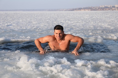 Man immersing in icy water on winter day. Baptism ritual