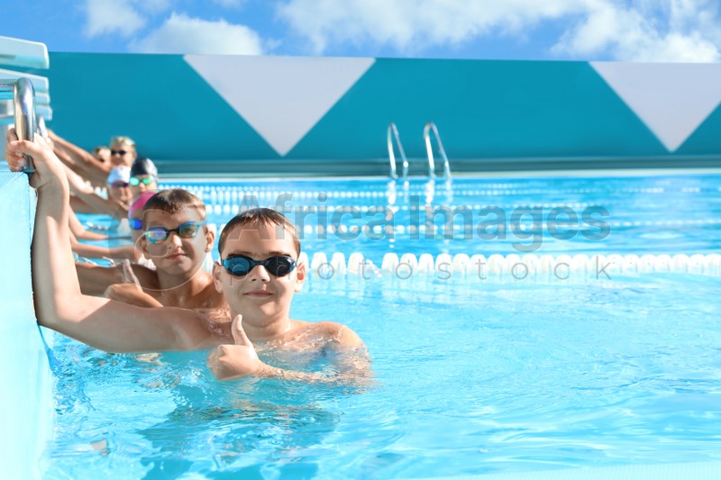 OCHAKIV, UKRAINE - JULY 09, 2020: Group of children in outdoor swimming pool on sunny day. Summer camp "Sportium"