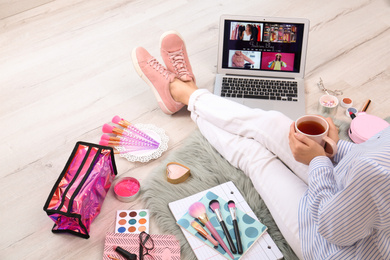 Beauty blogger with laptop and cosmetics sitting on floor, closeup