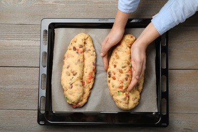 Woman making Stollen with candied fruits and nuts on baking tray at wooden table, top view. Baking traditional German Christmas bread